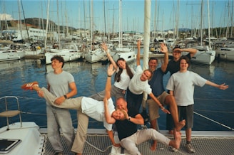 Group of friends posing on a sailboat dock.