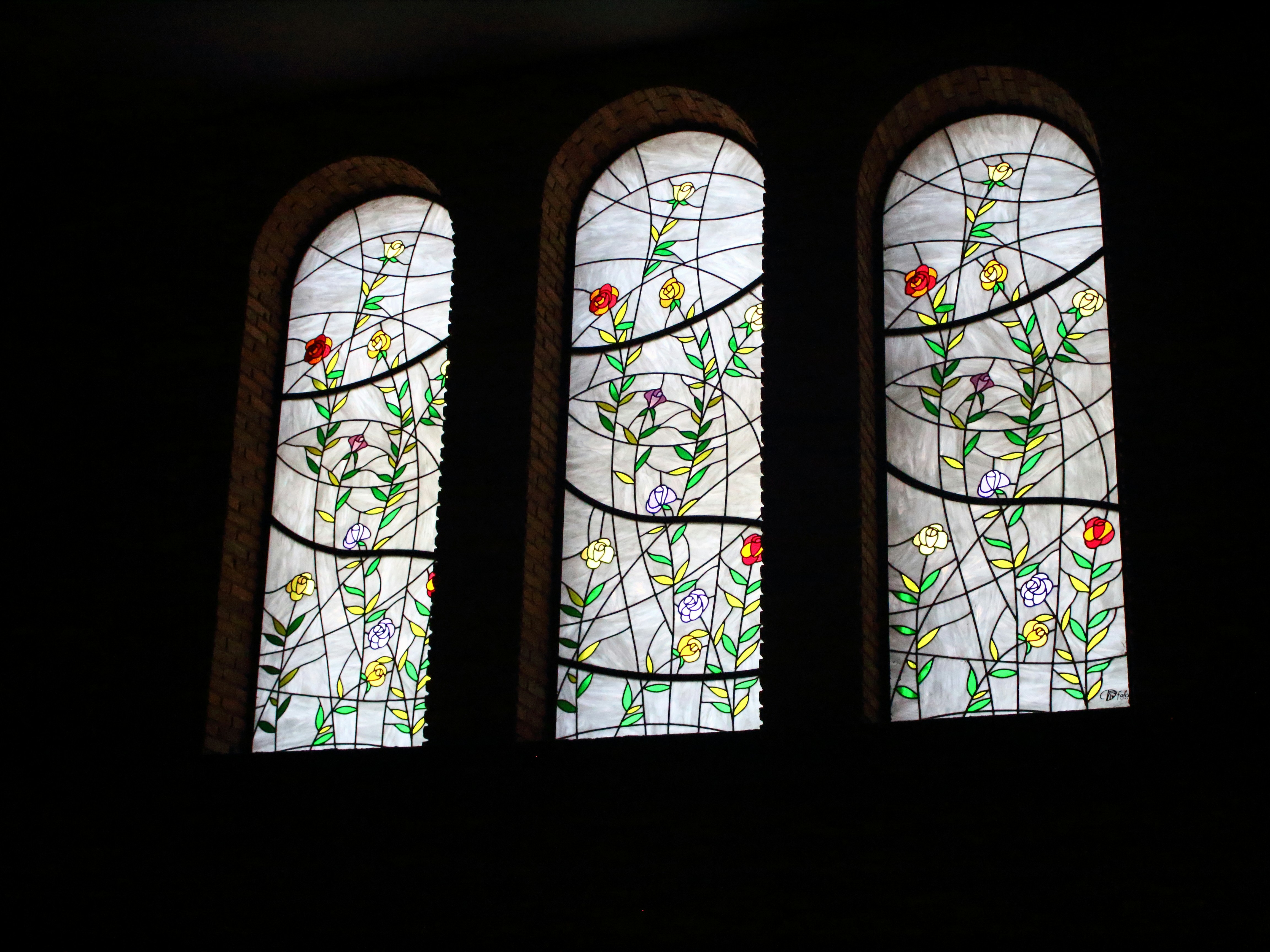 Trois vitraux cintrés à motifs floraux.