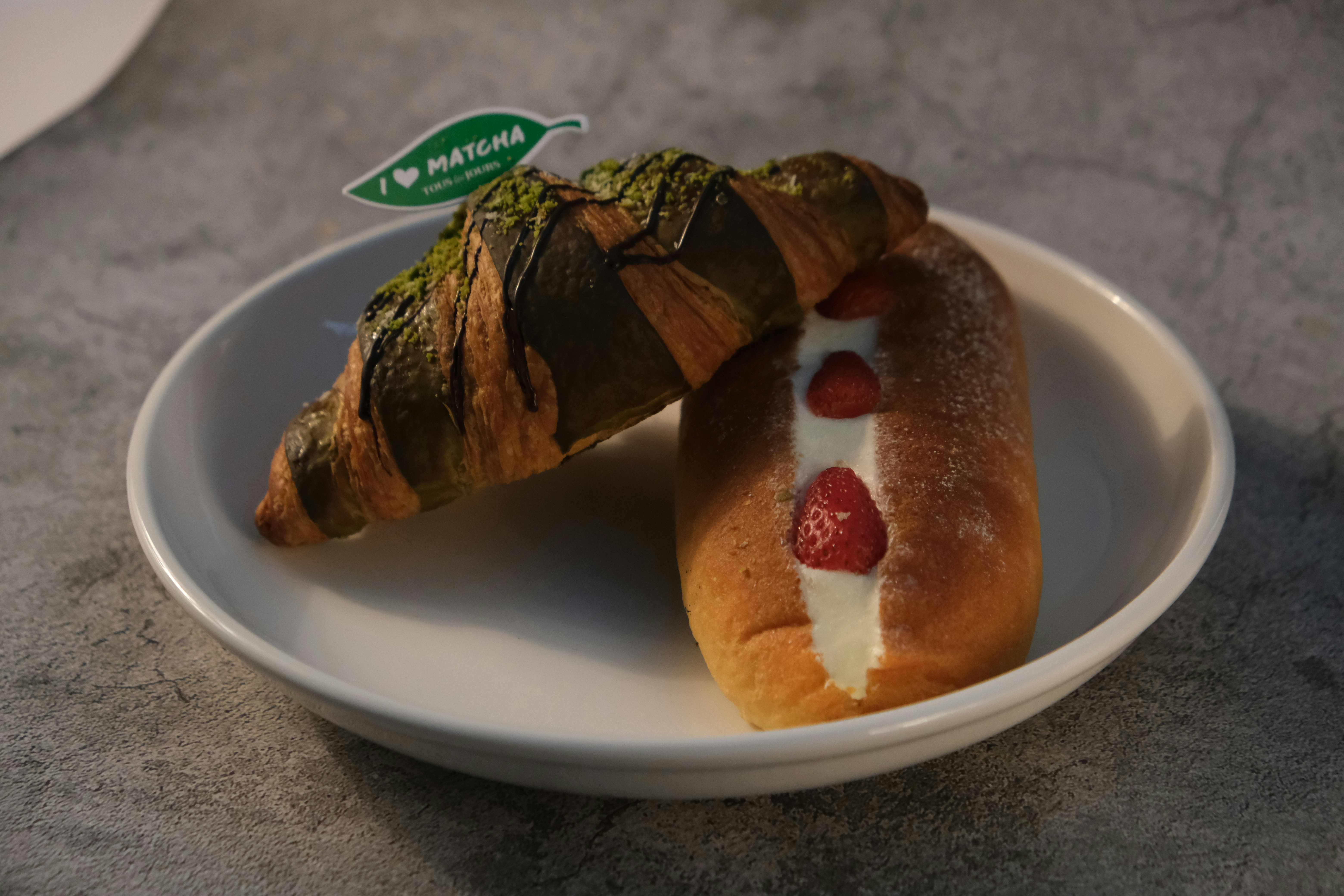 Matcha-Croissant und Erdbeercreme-Gebäck auf dem Teller.