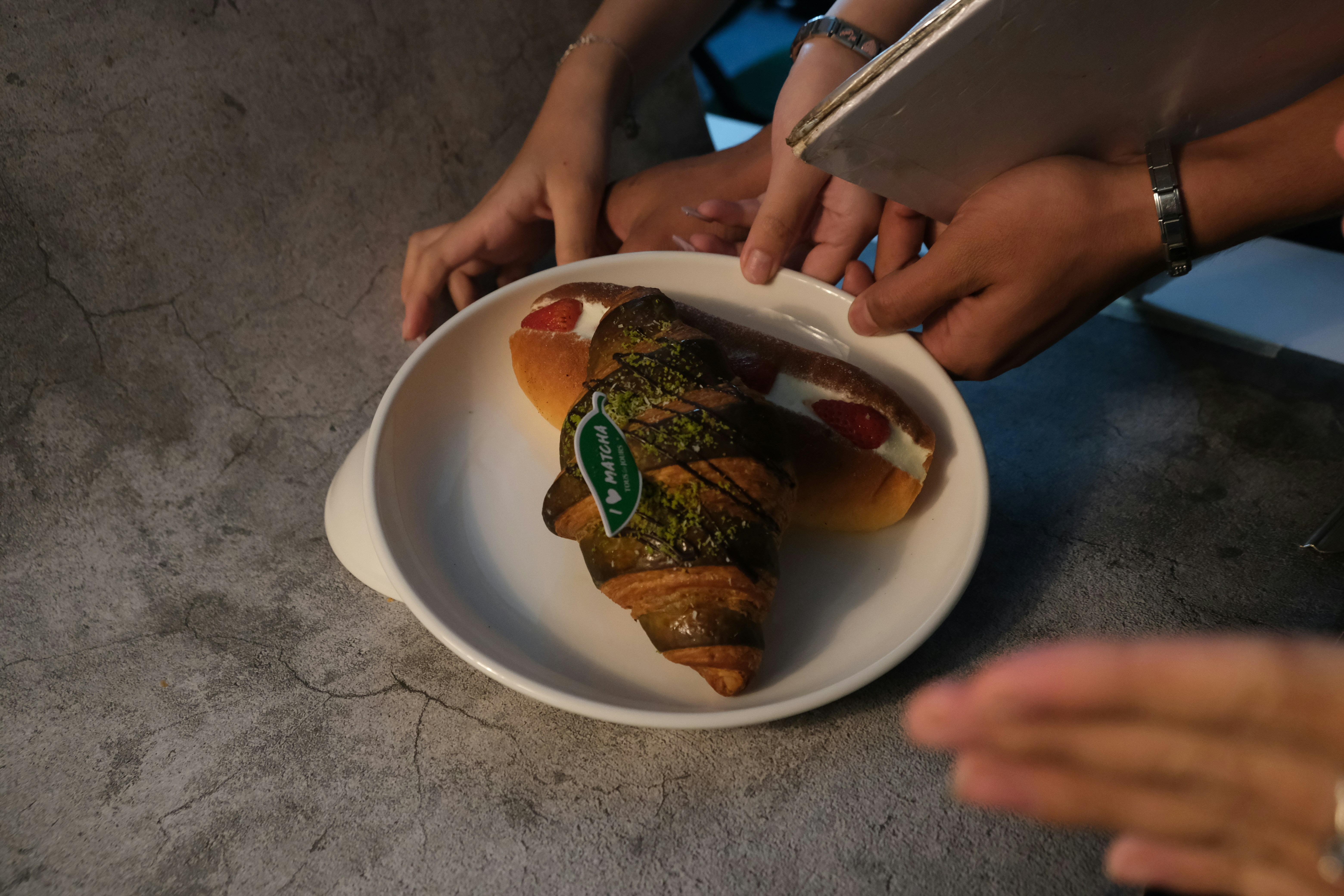 Croissant und Hot Dog auf einem weißen Teller.