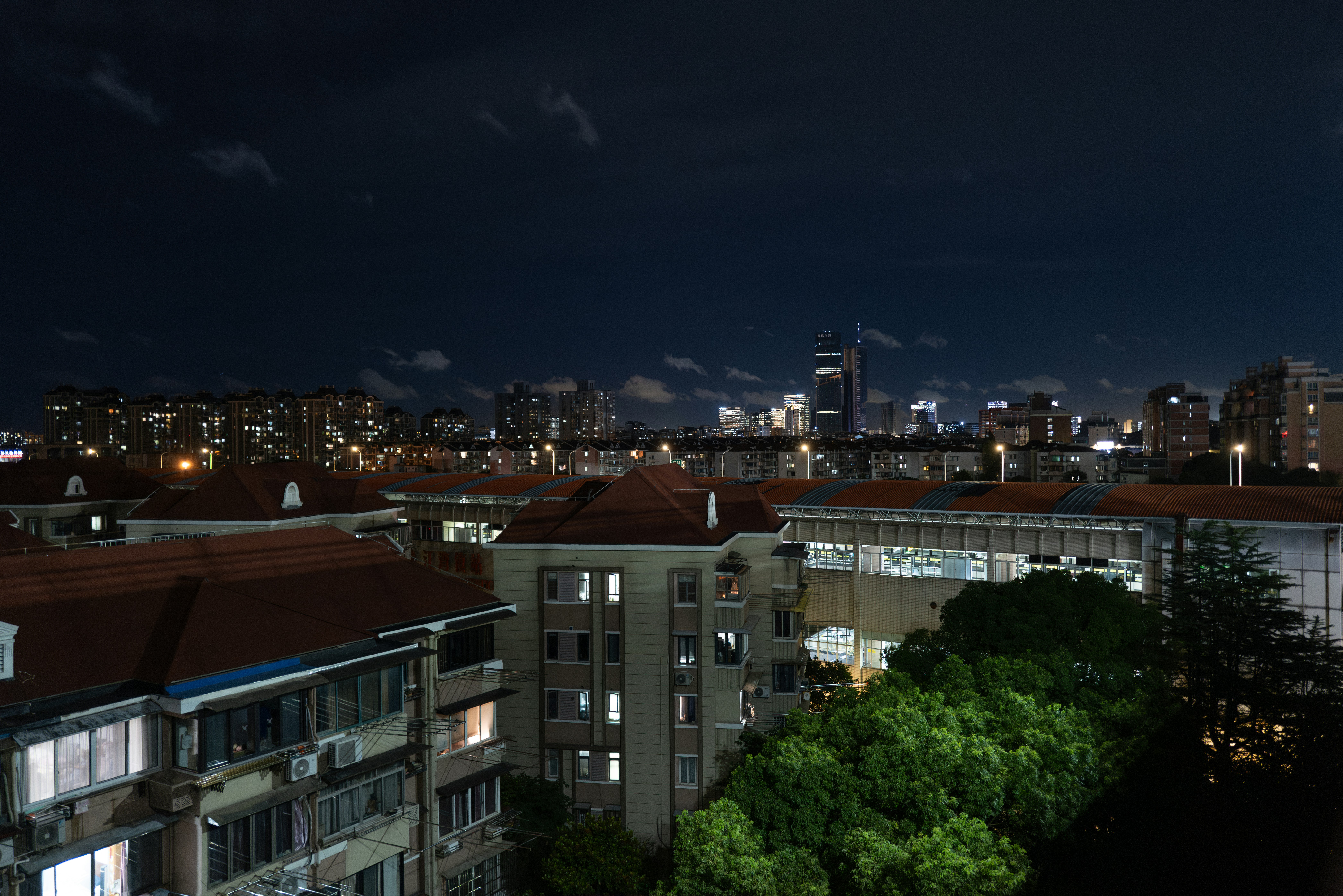 City skyline at night with illuminated buildings and trees.