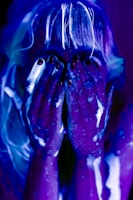 Woman covered in glowing paint under blacklight