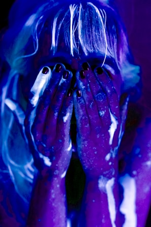 Woman covered in glowing paint under blacklight