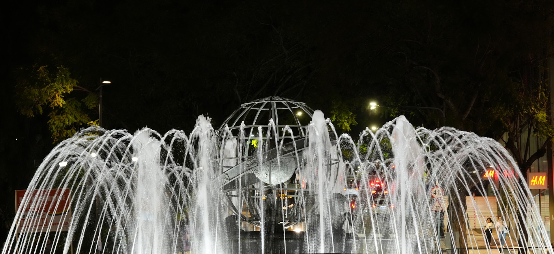 A fountain spraying water at night with lights.