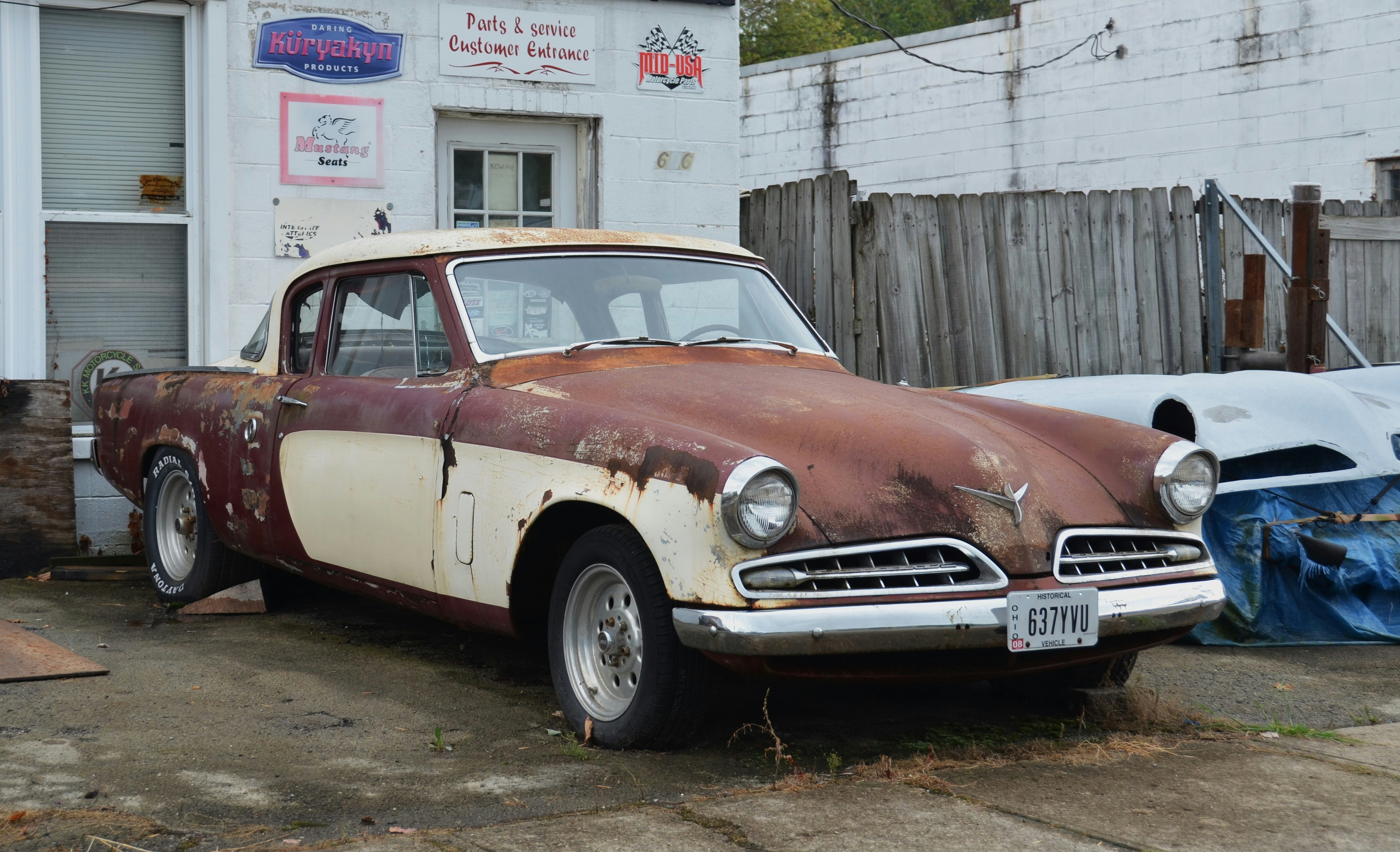 A rusty vintage car parked outside a building