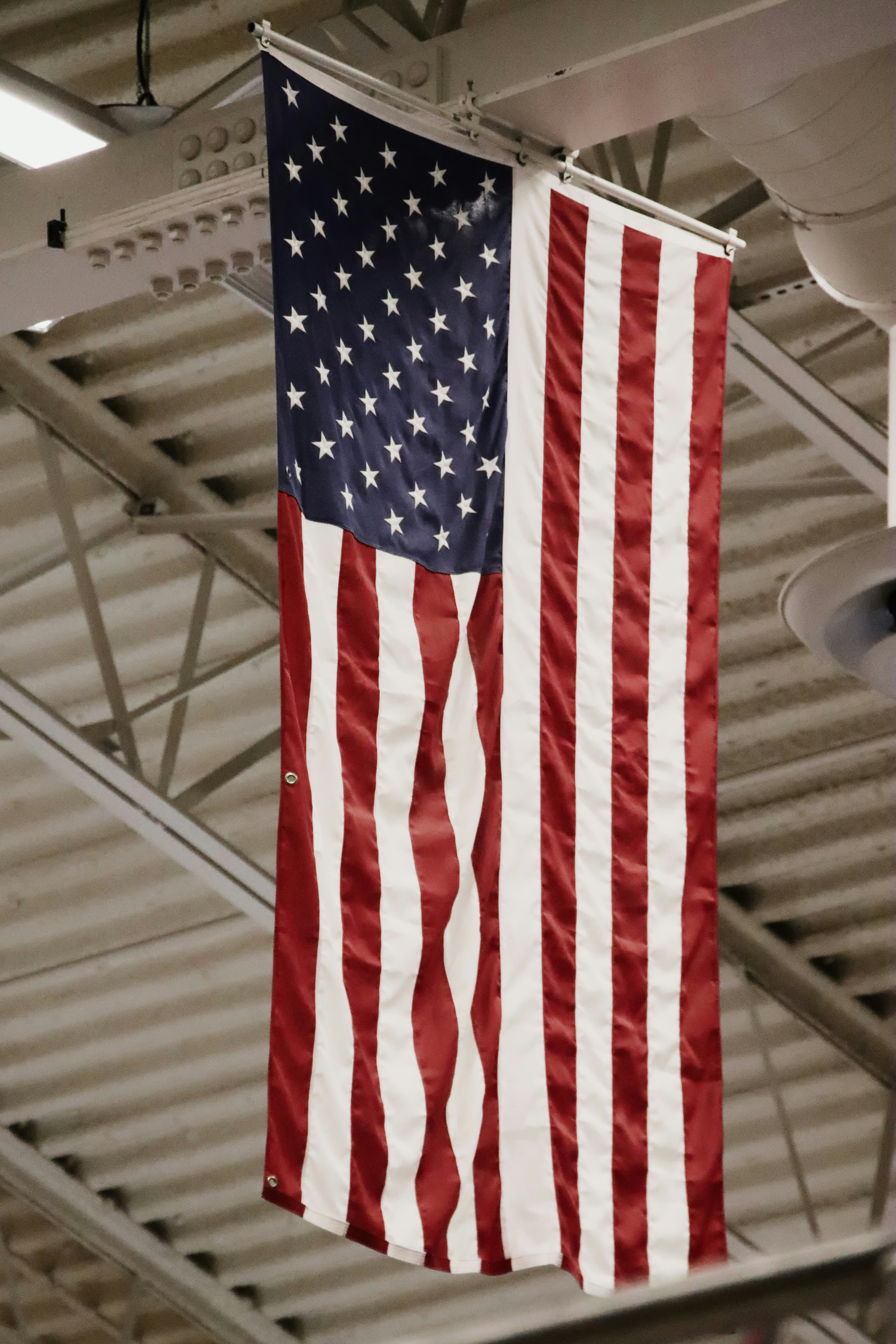 American flag hanging indoors from ceiling beams.