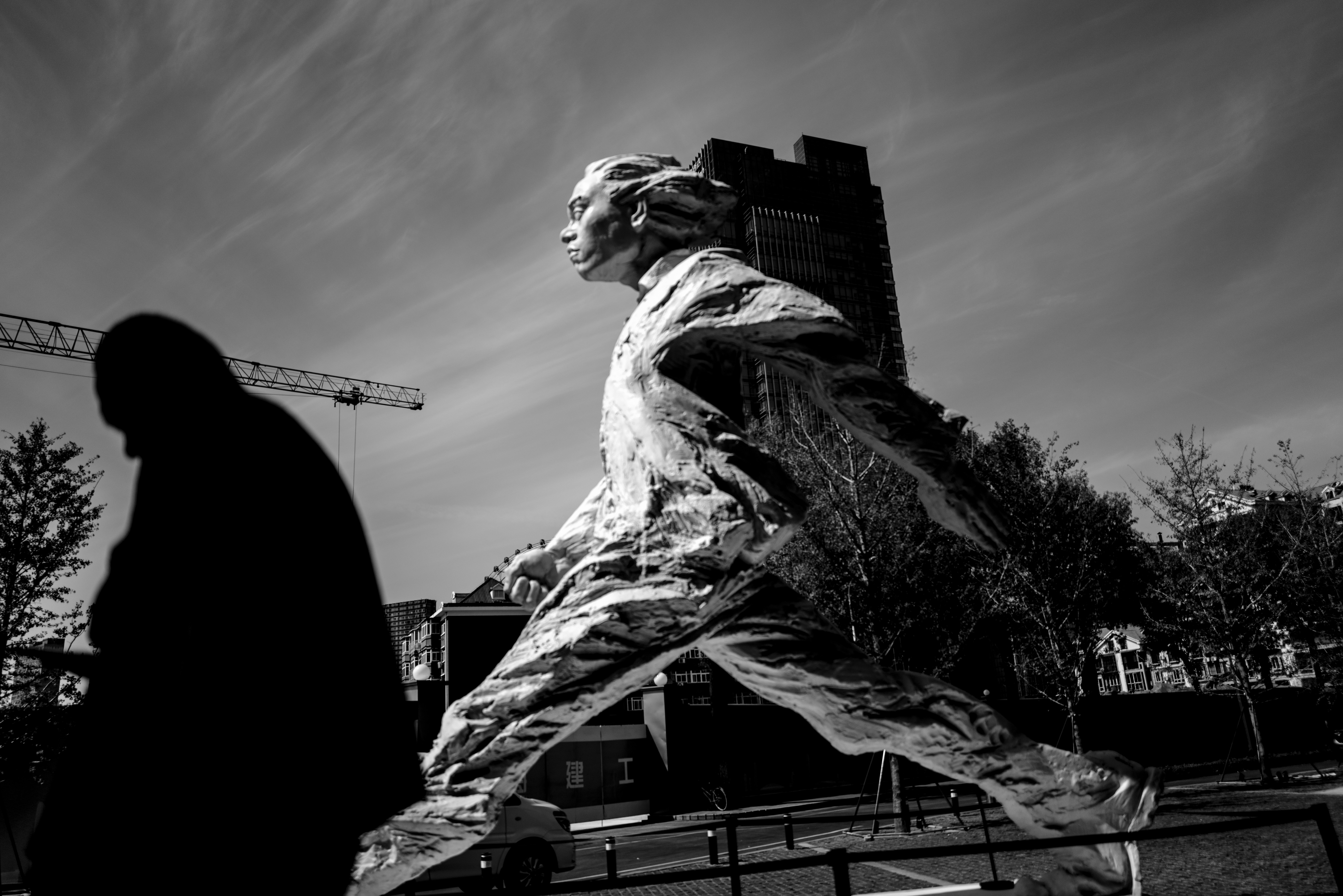 Escultura de una persona caminando contra un edificio