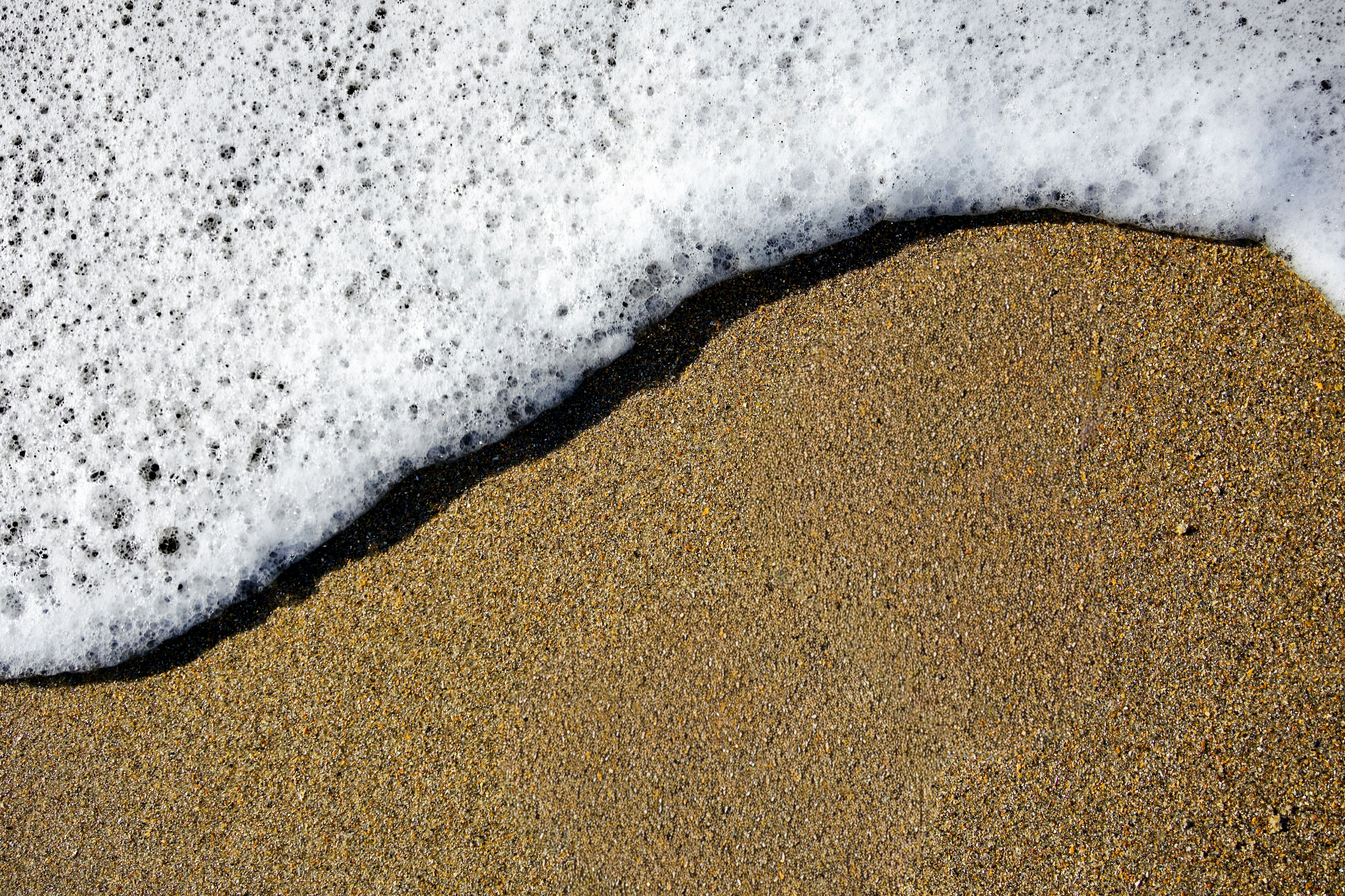 L’écume de la mer blanche se répand sur la plage de sable