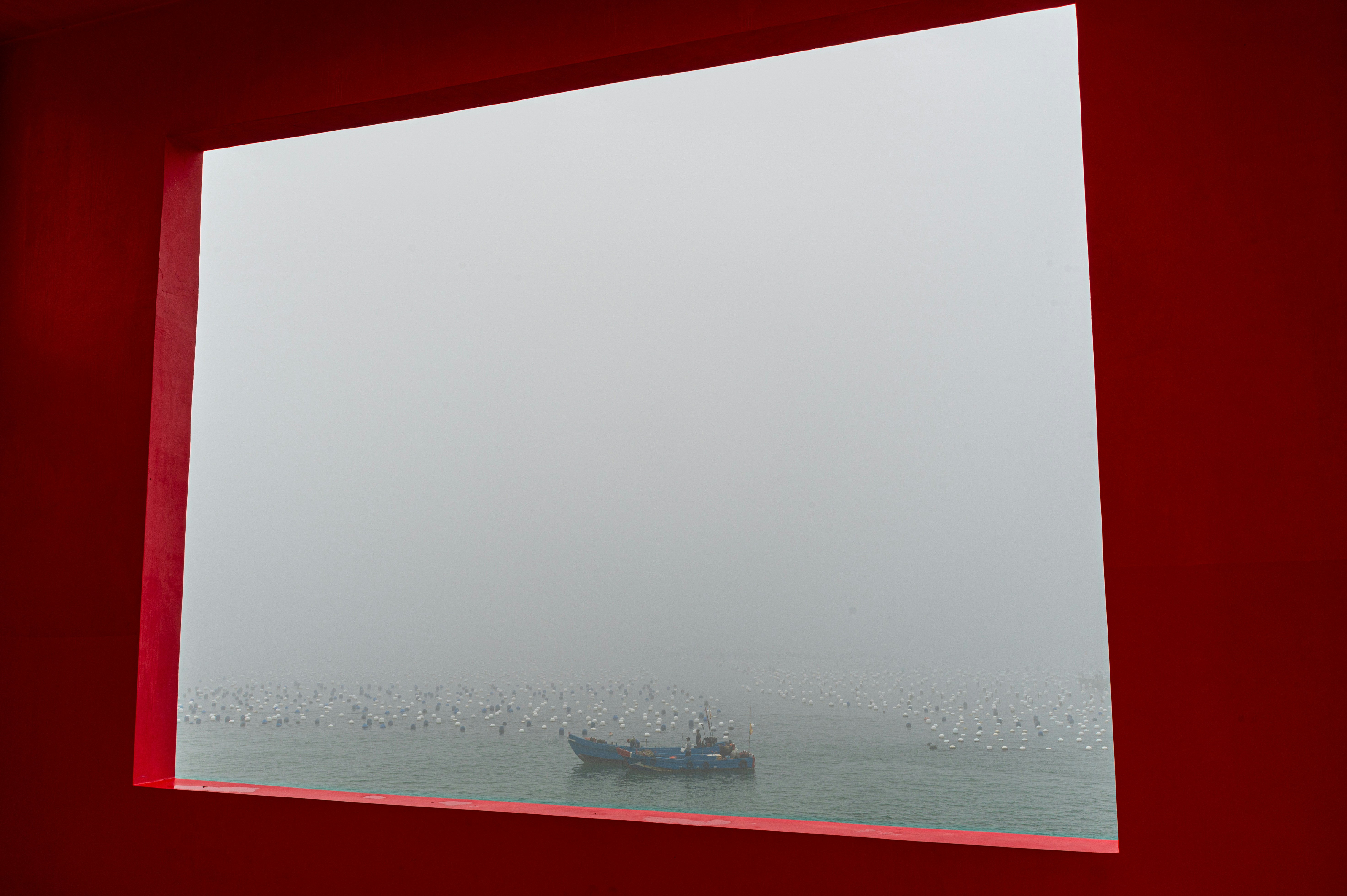 A lone boat sails on a foggy sea