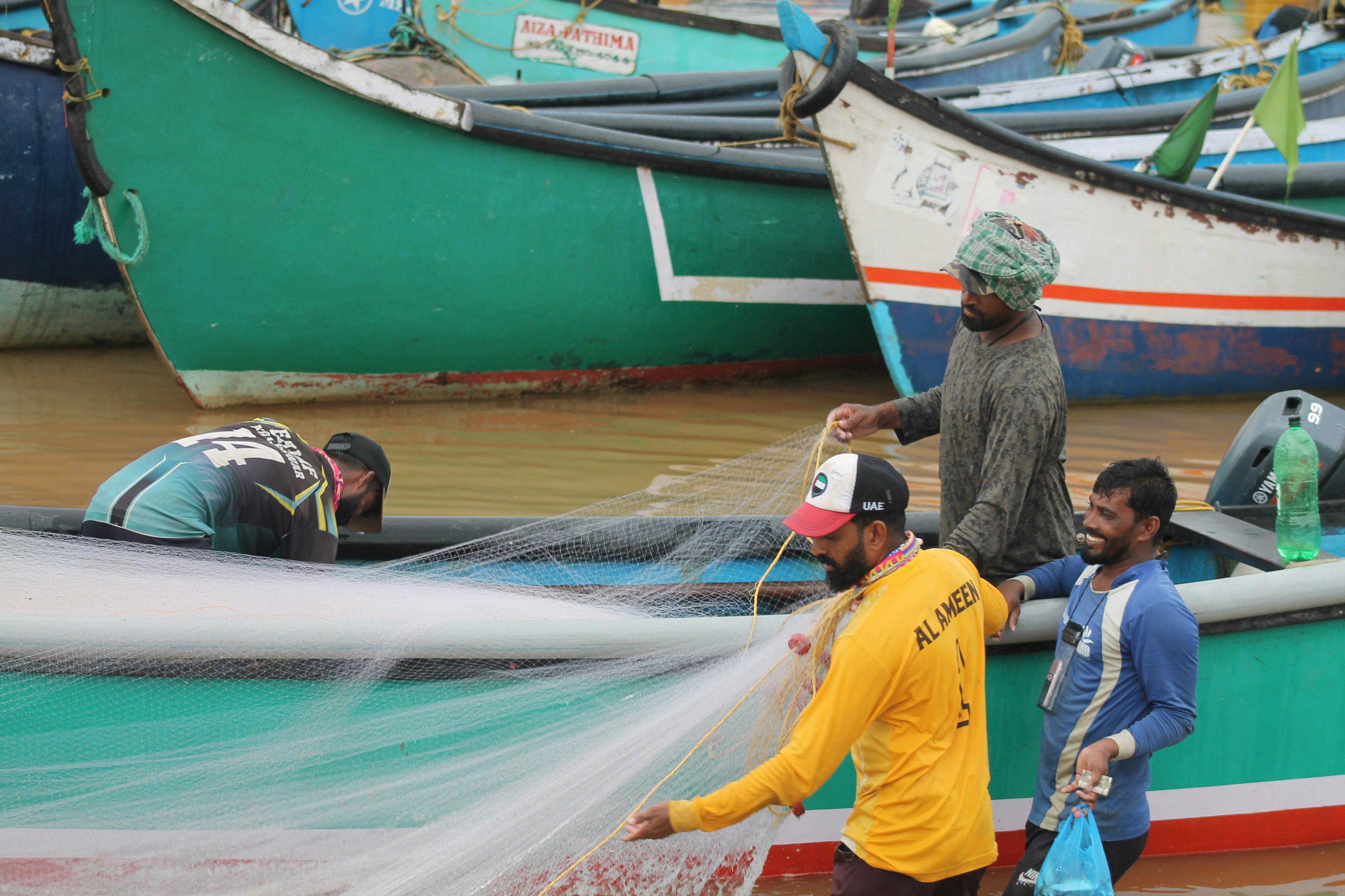 Fishermen untangling a large fishing net together.