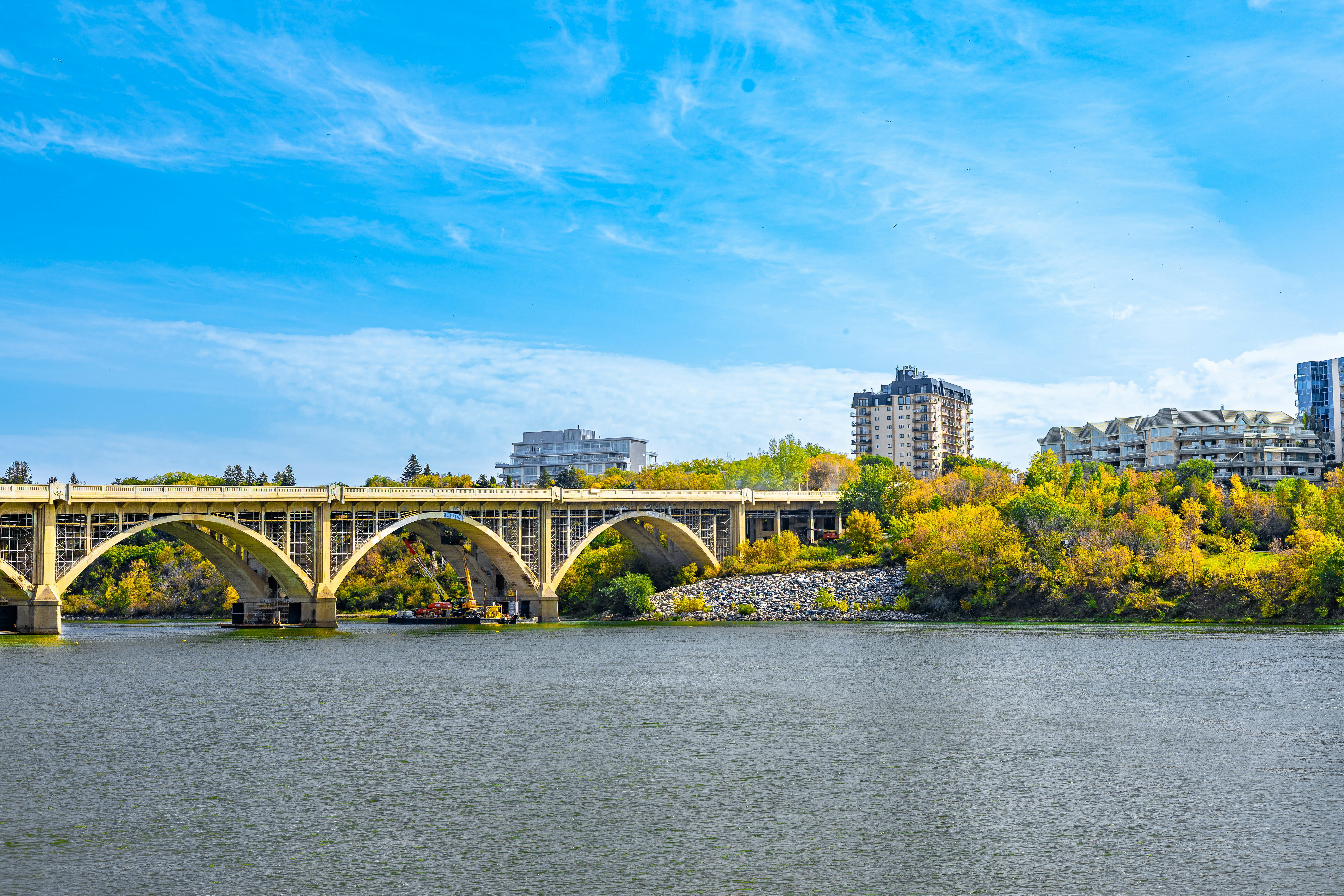 Arch bridge over a river with autumn foliage.