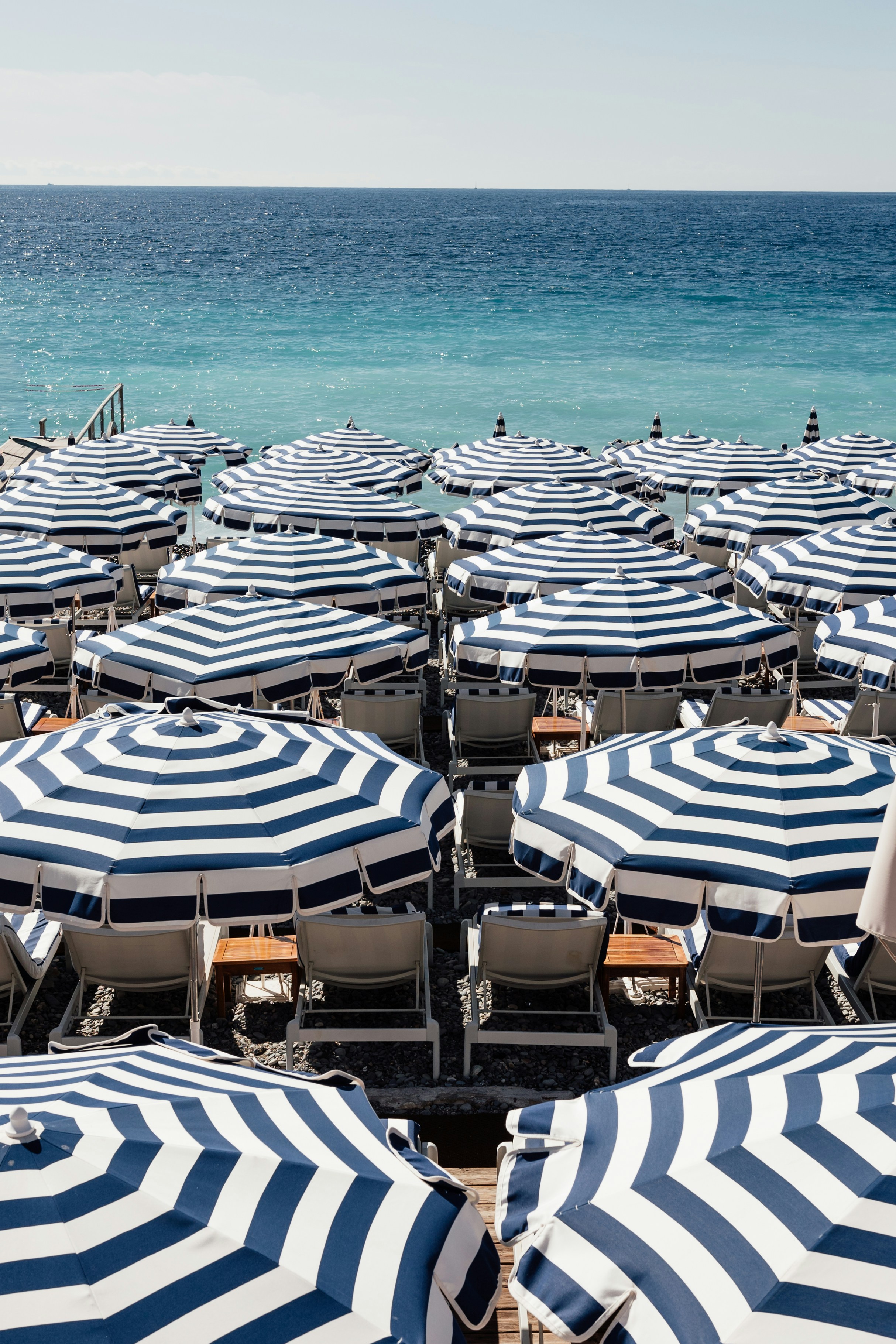 Rows of striped umbrellas on a sunny beach.