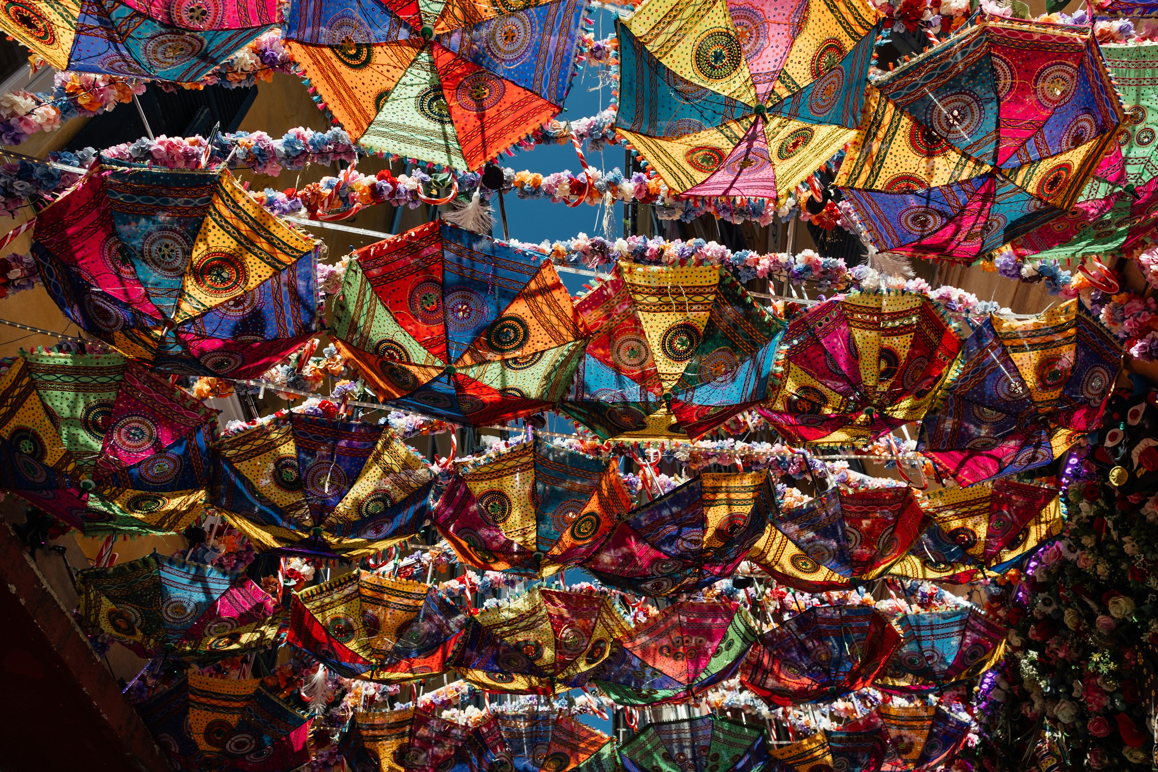 Colorful patterned umbrellas hanging overhead in a market.