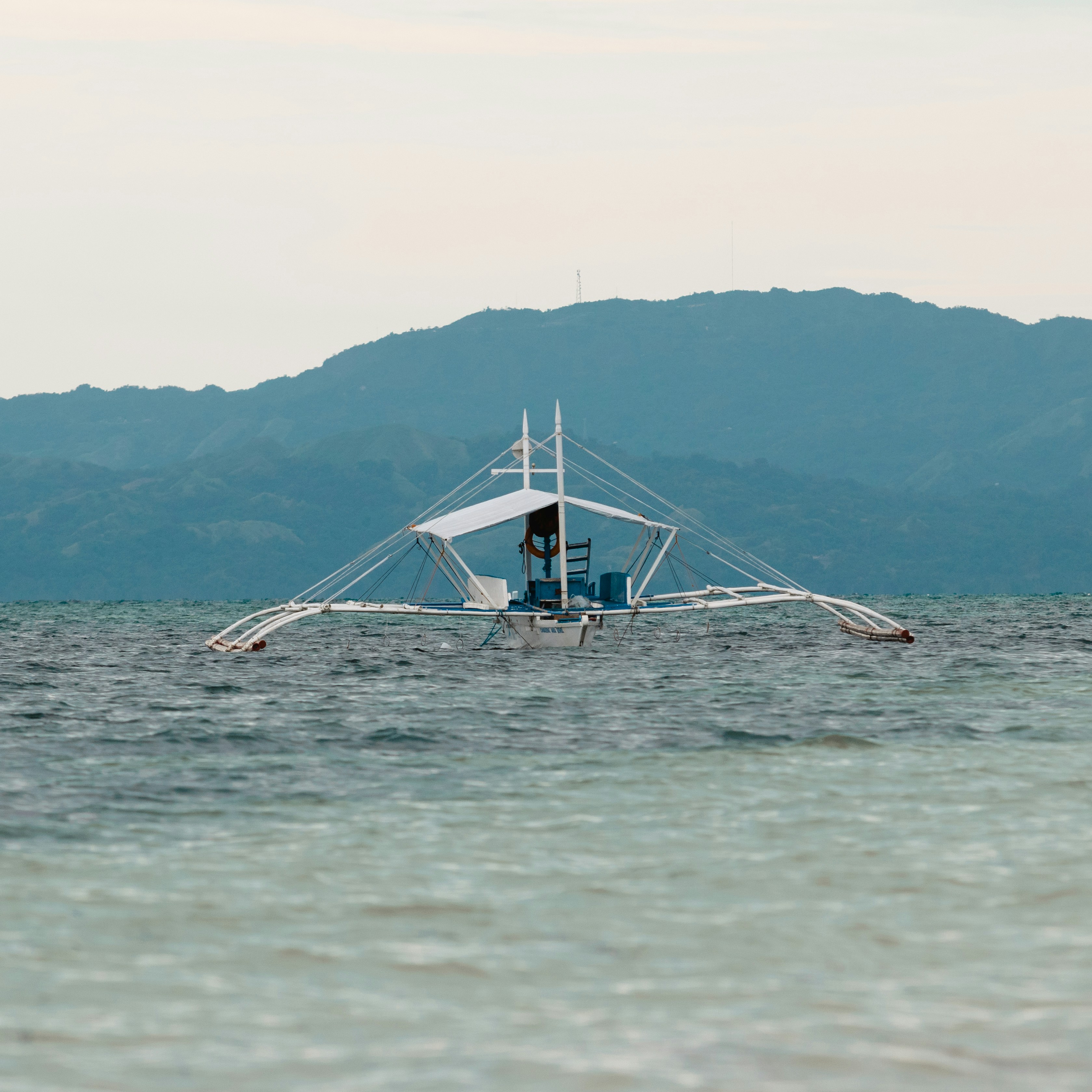 A traditional outrigger boat sails on the ocean.
