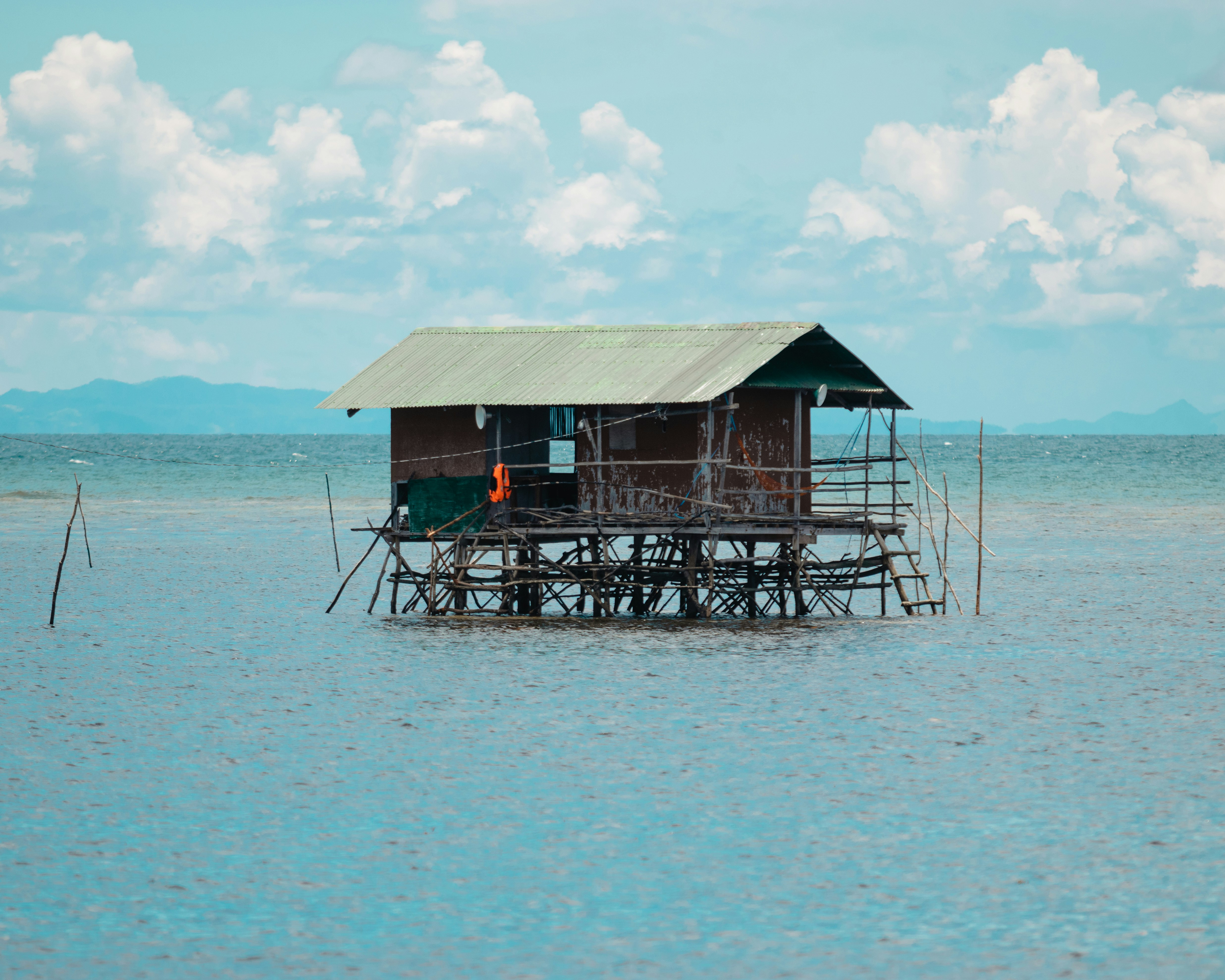 Una pequeña casa sobre pilotes se encuentra en aguas turquesas poco profundas.