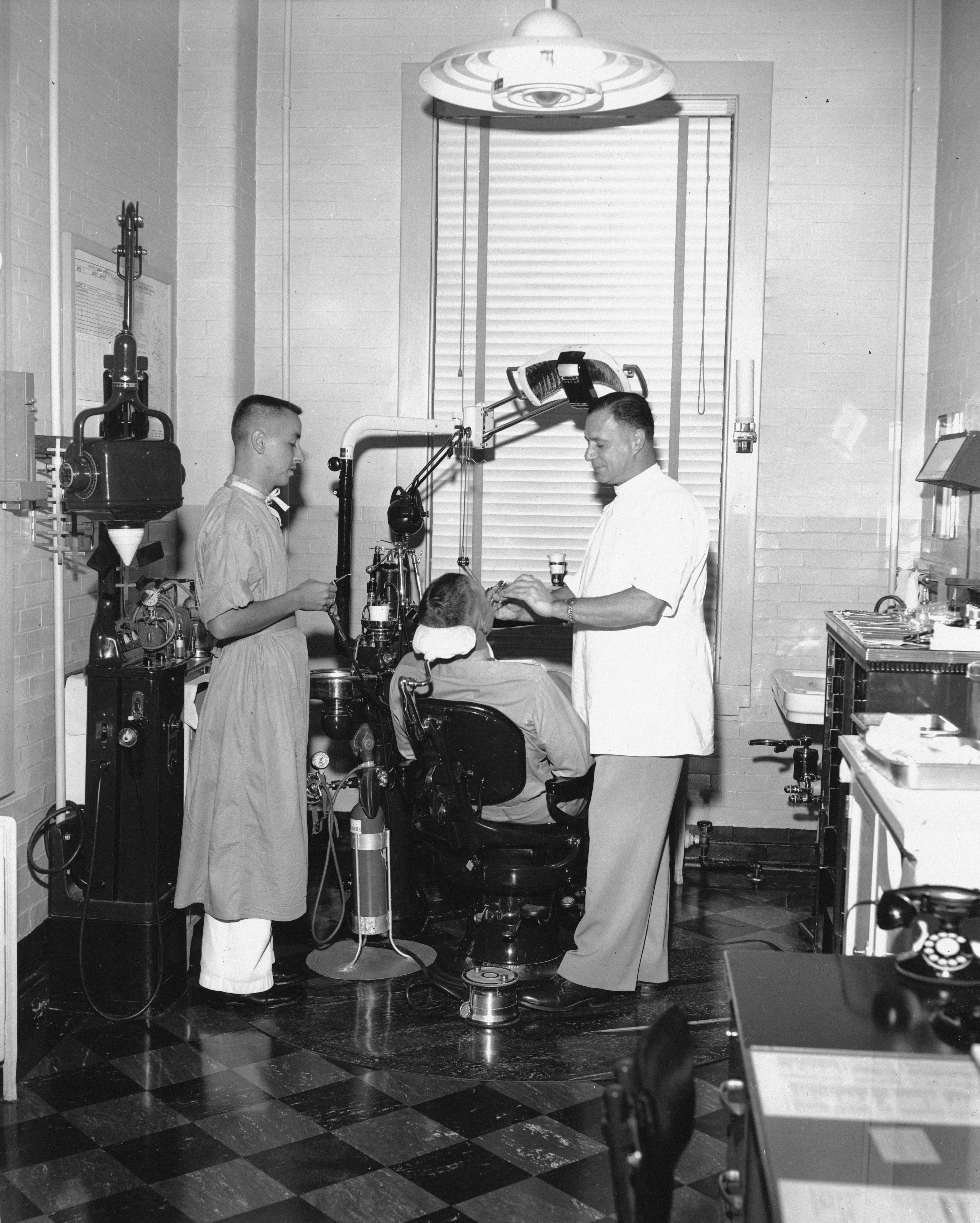 Dentist and assistant working on patient in vintage dental office.