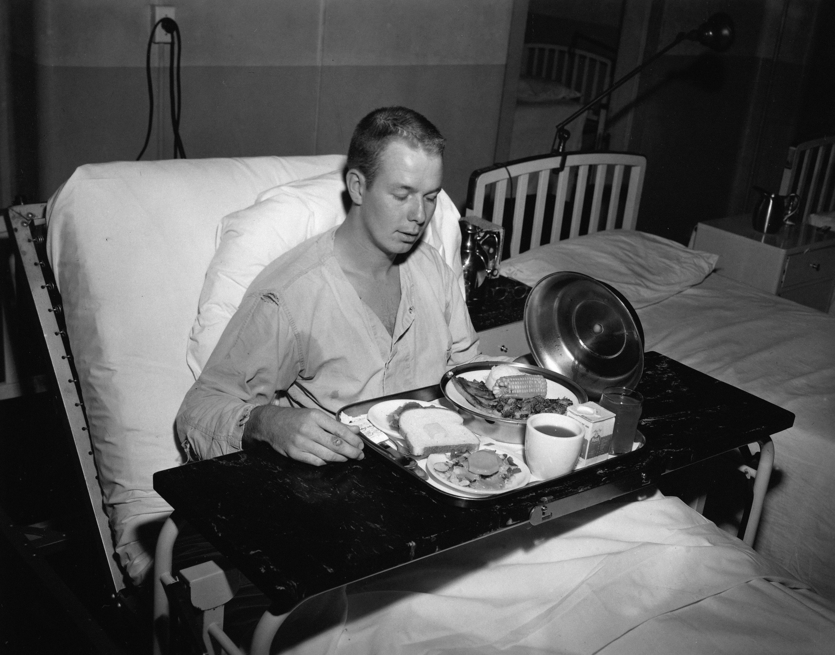 Un homme dans un lit d’hôpital en train de manger un repas