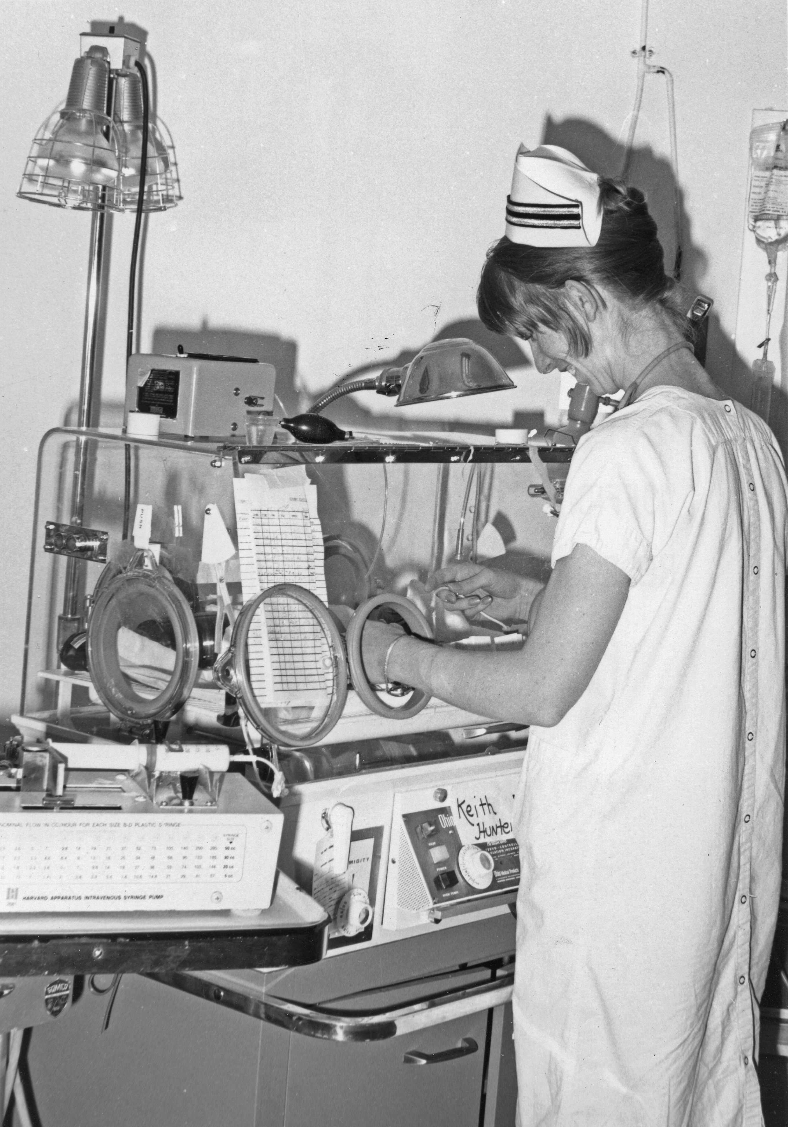 Enfermera atendiendo al bebé en incubadora