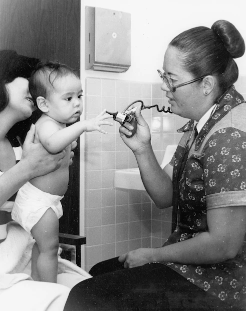 Nurse examines a baby with a stethoscope.