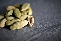 A pile of dried cardamom pods on a dark surface.