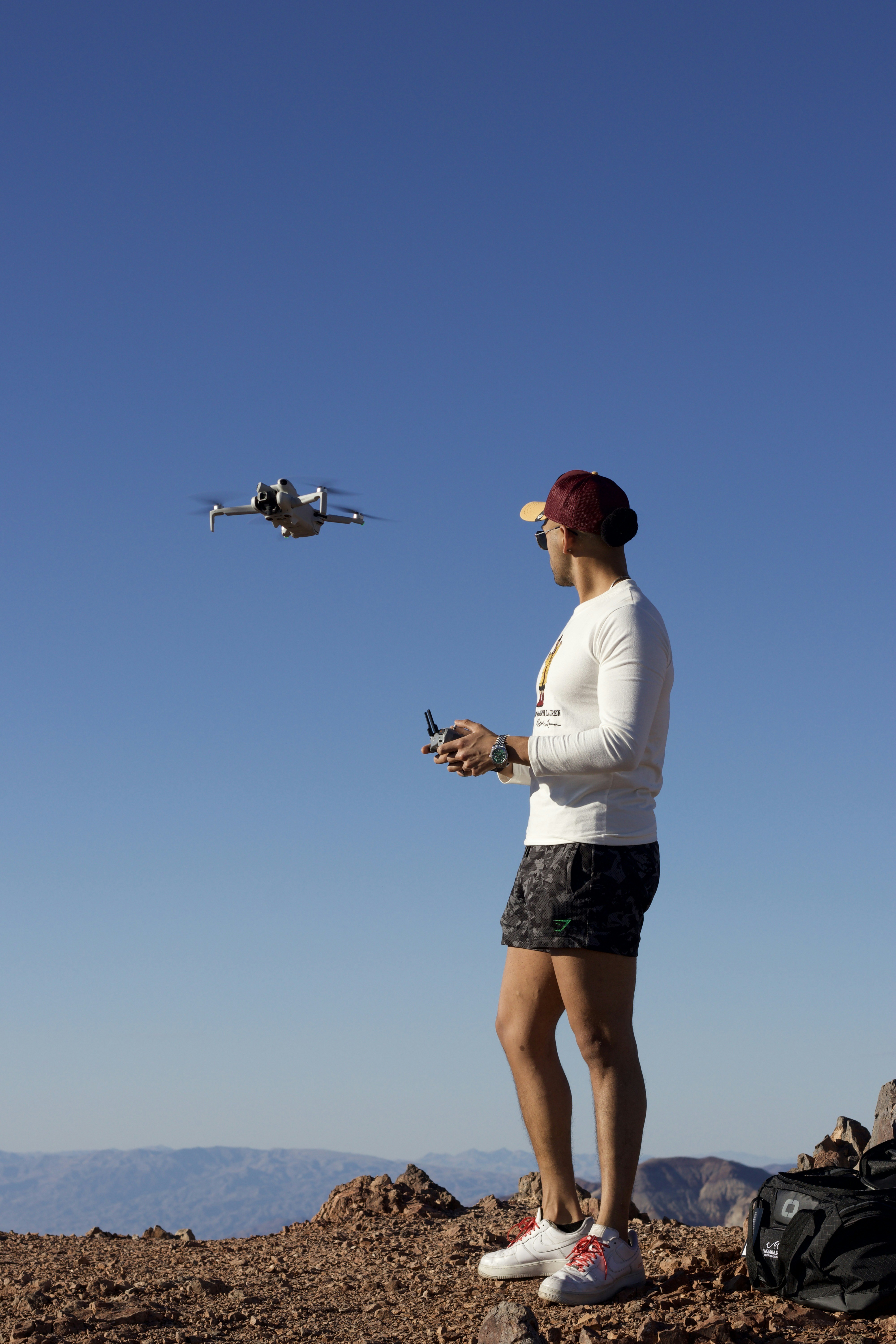Man controlling drone with remote on mountain peak
