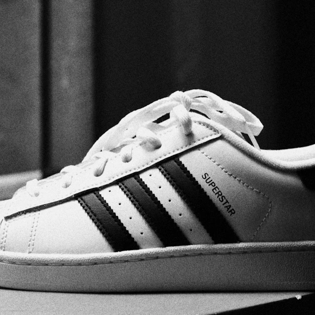 A white adidas Superstar sneaker with black stripes and the rubber shell toe