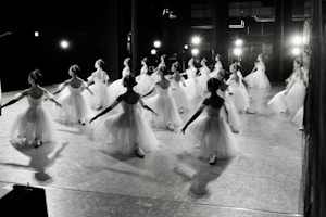 Dancers in white tutus practice on a stage