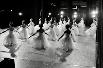 Dancers in white tutus practice on a stage