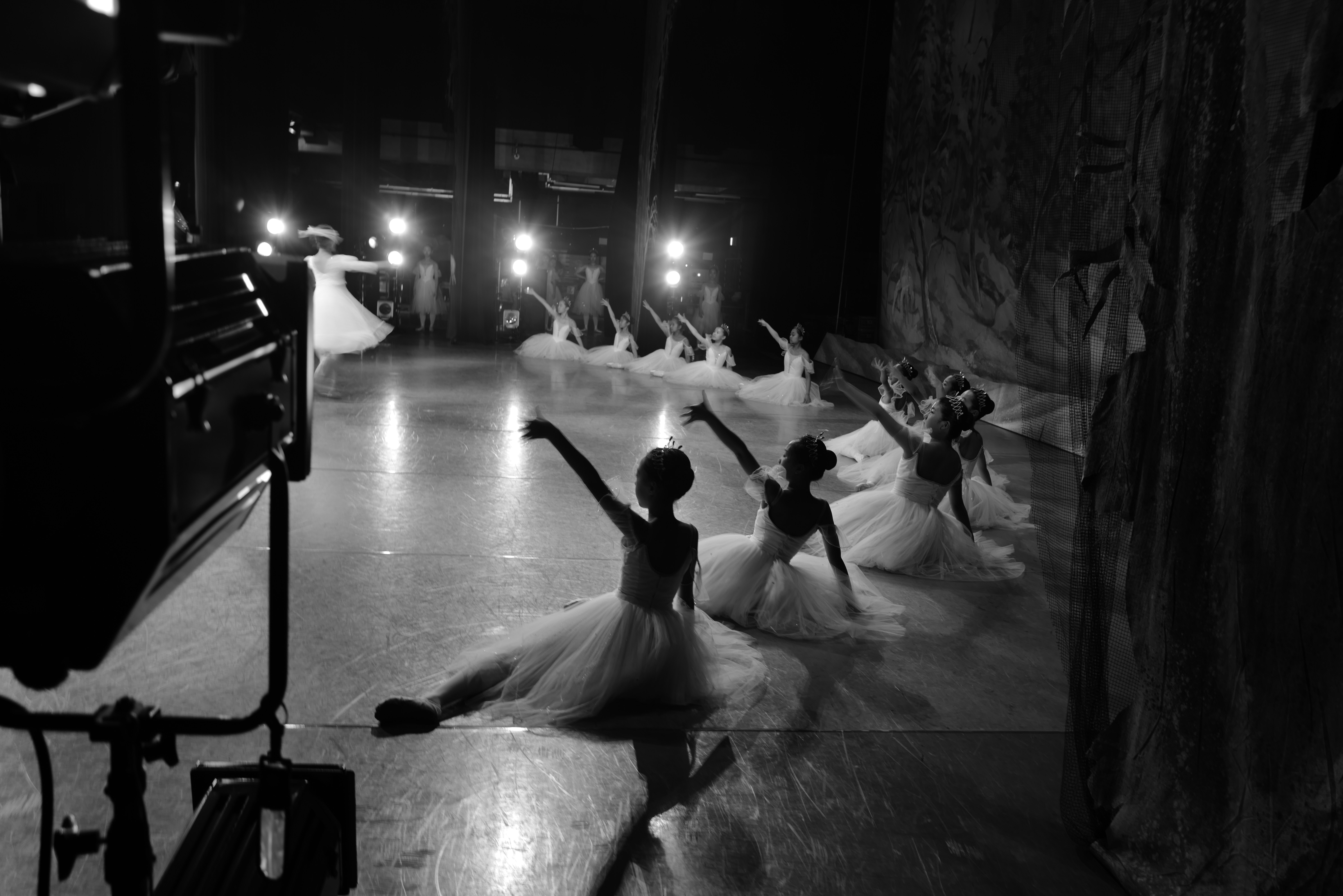 Ballet dancers in tutus perform on stage with spotlights