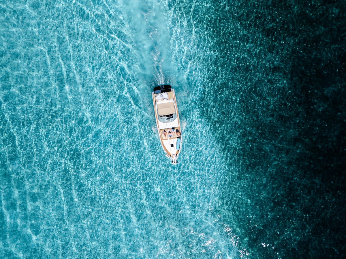 A boat sails across clear blue ocean water.