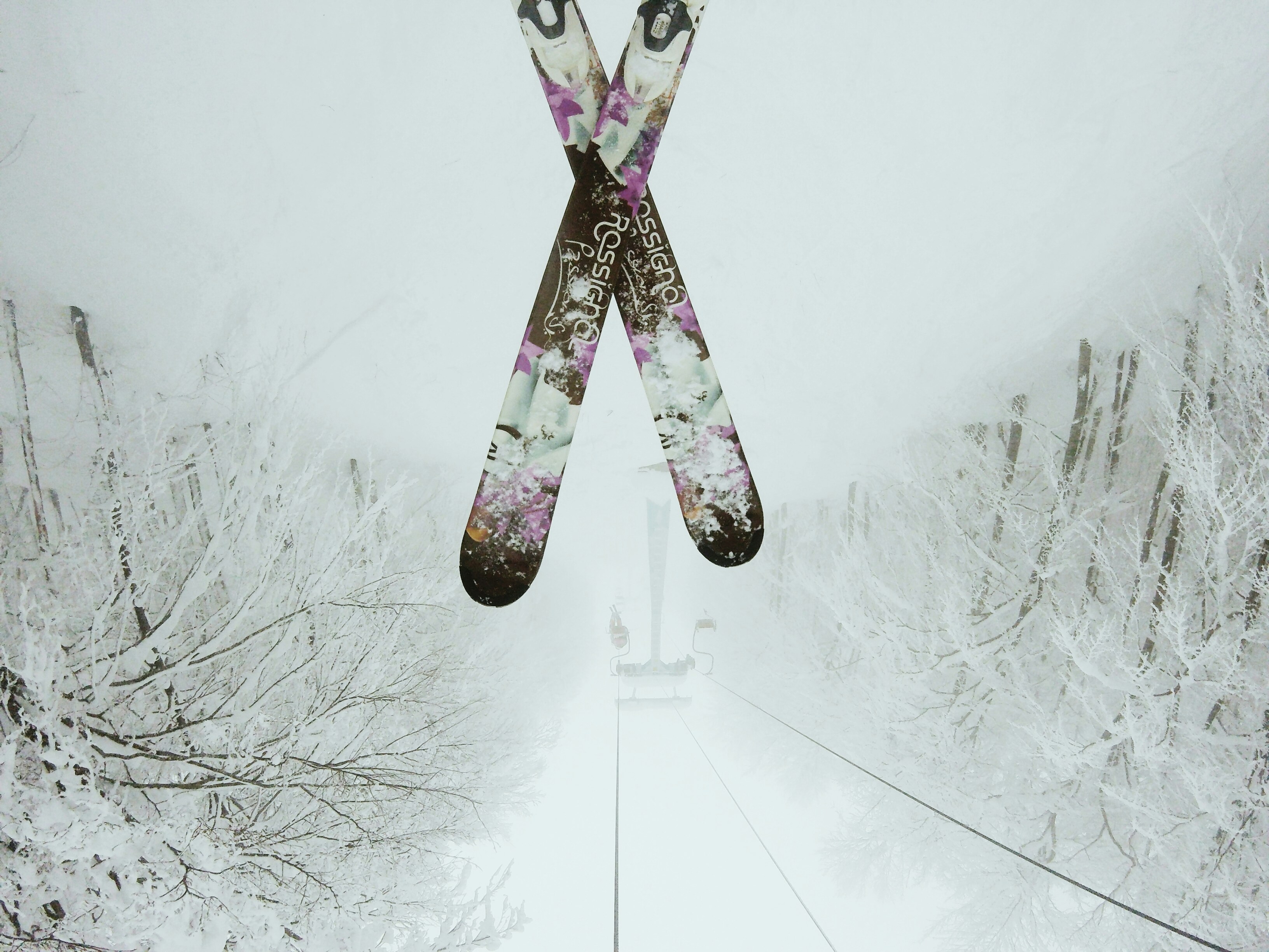 Rossignol skis on a chair lift going up a mountain.