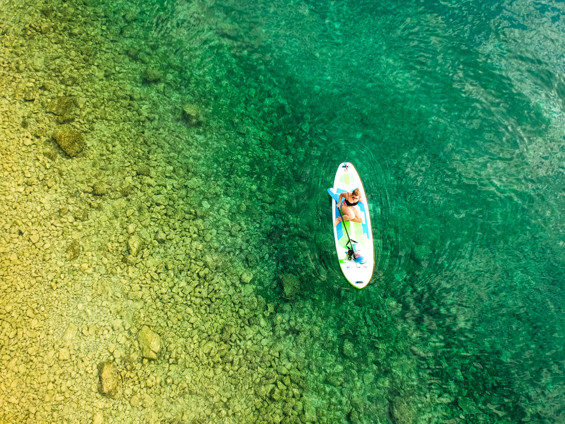 Woman paddleboarding across clear turquoise water at Lake Ohrid