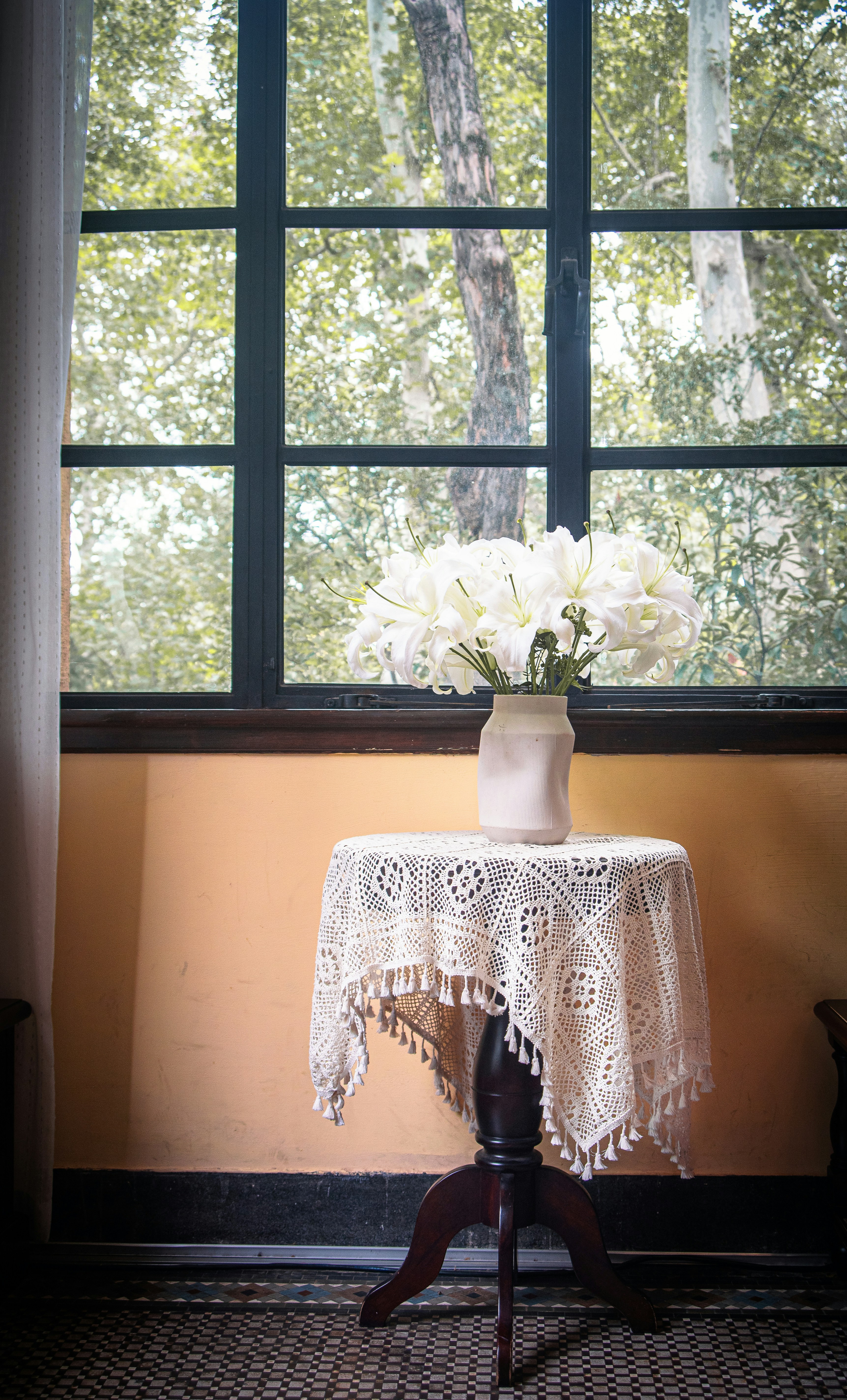 White lilies in a vase on a table by window