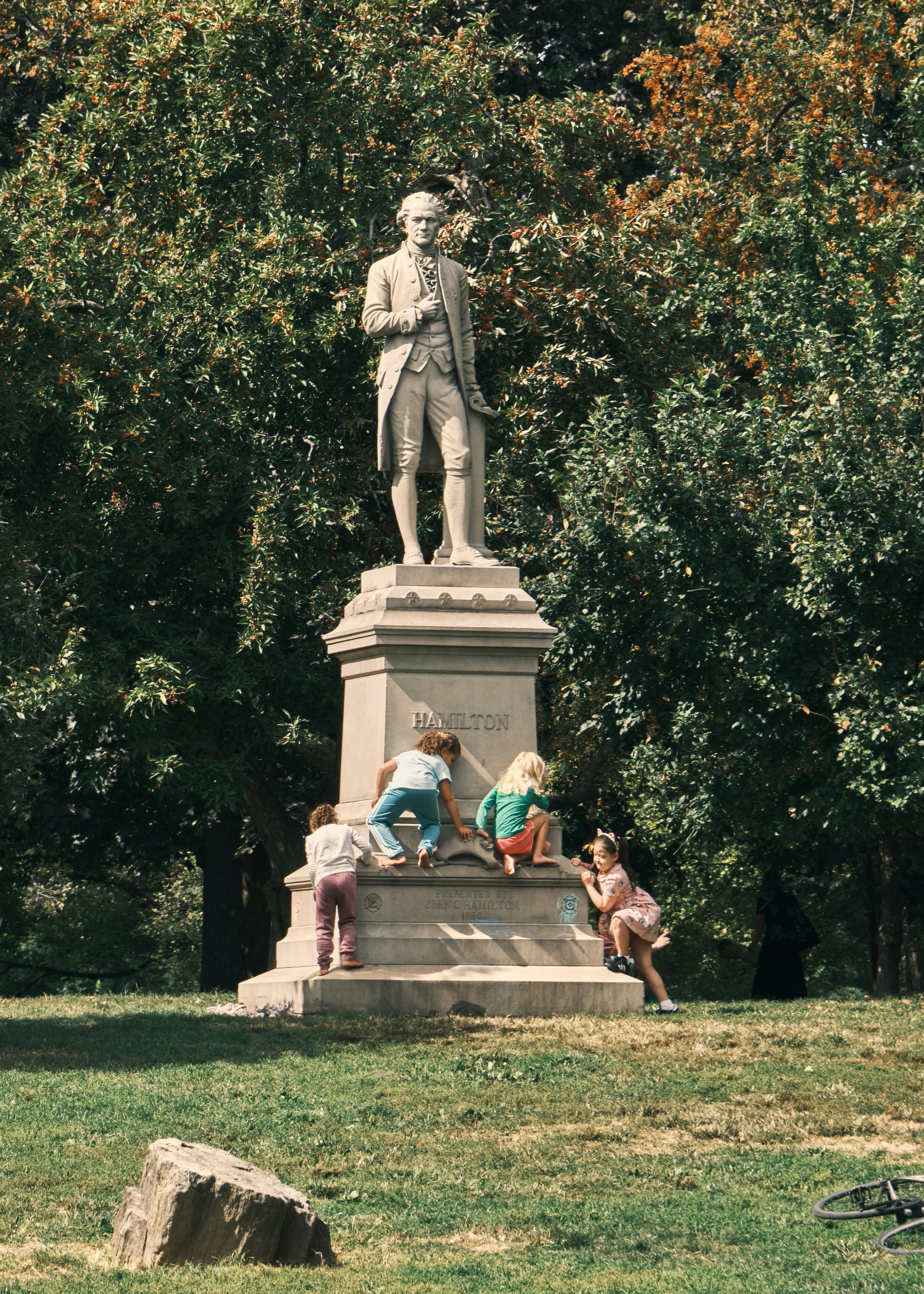 Children climbing on a statue in a park.