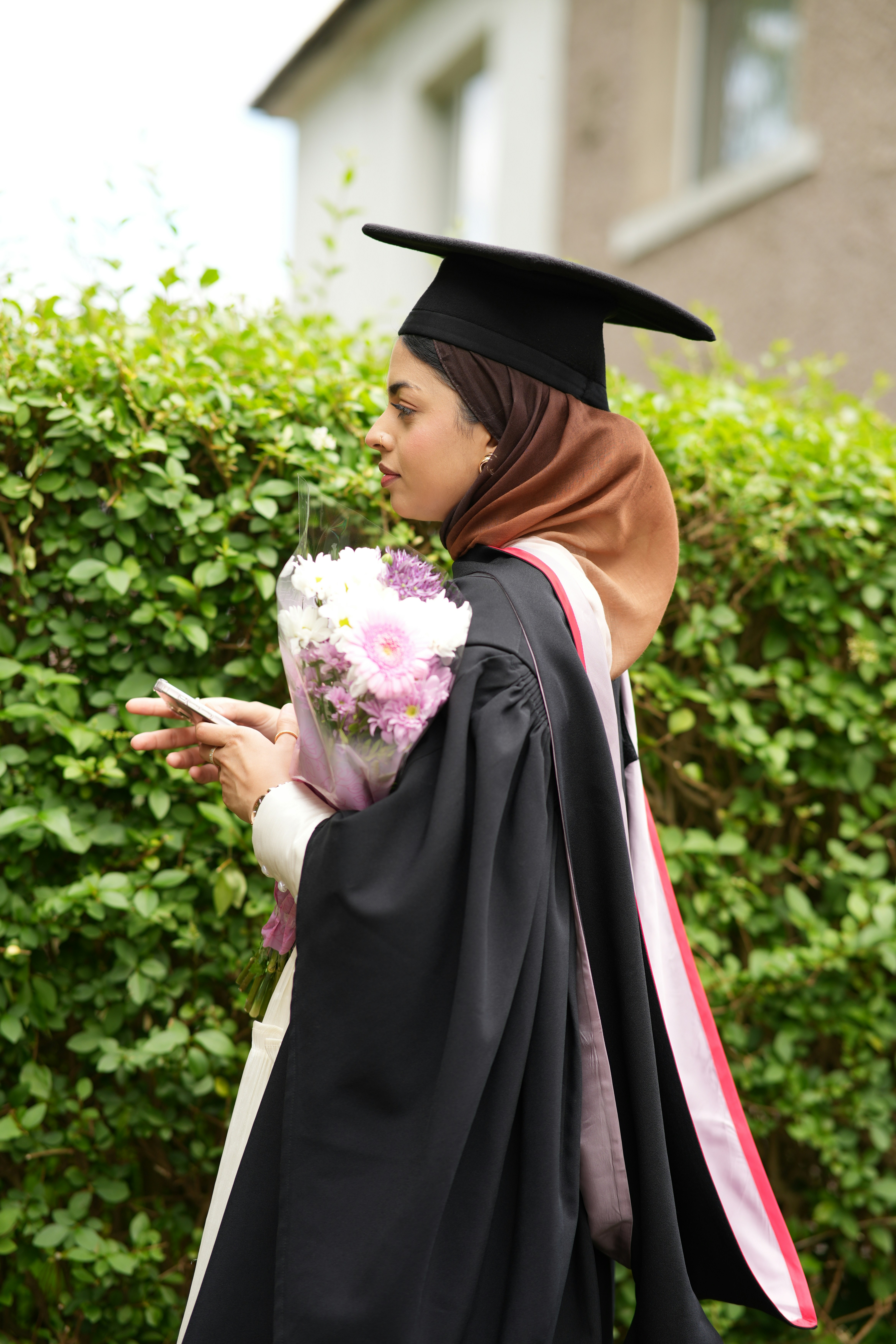 Young woman in graduation attire with flowers