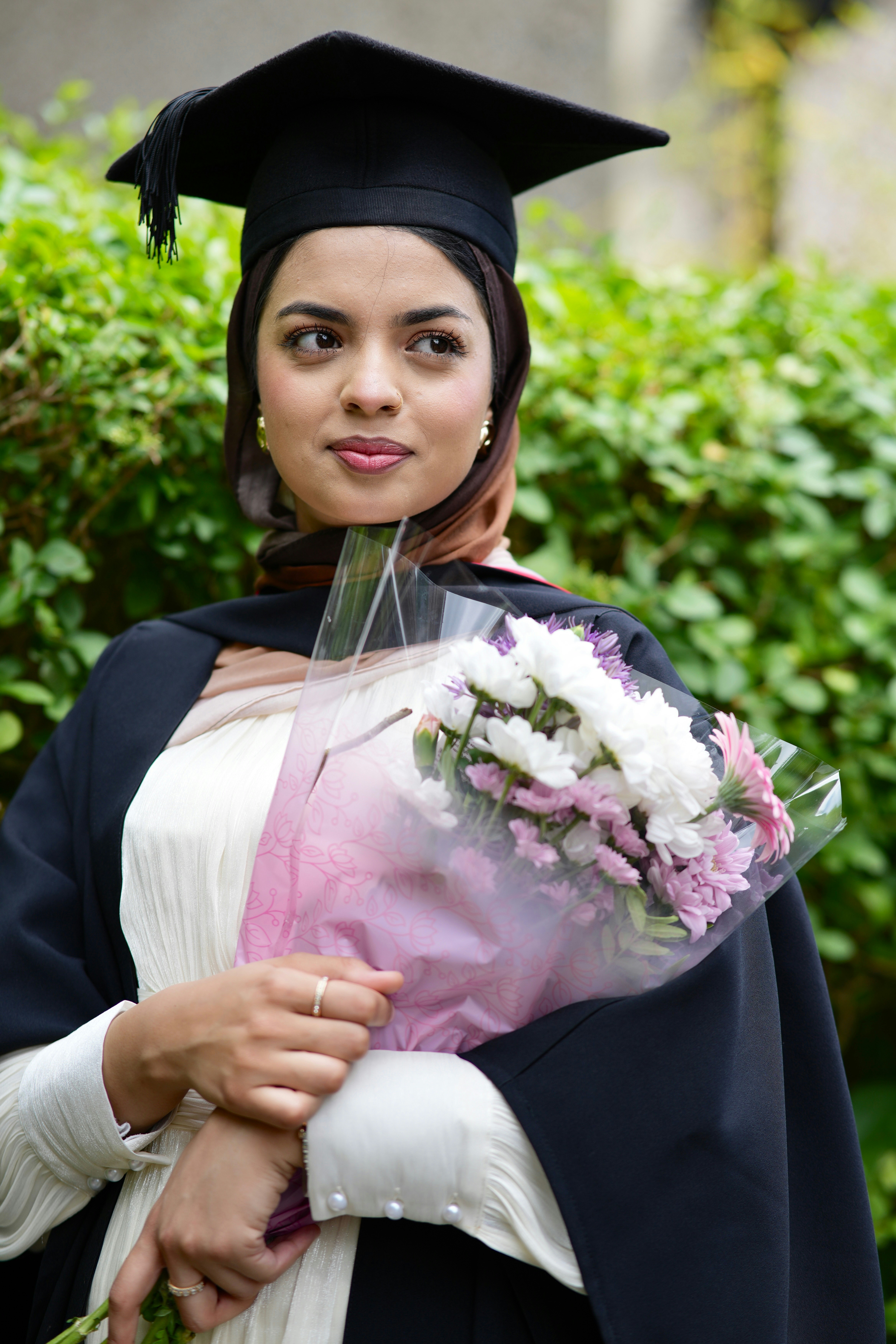 Graduate in cap and gown with a flower bouquet