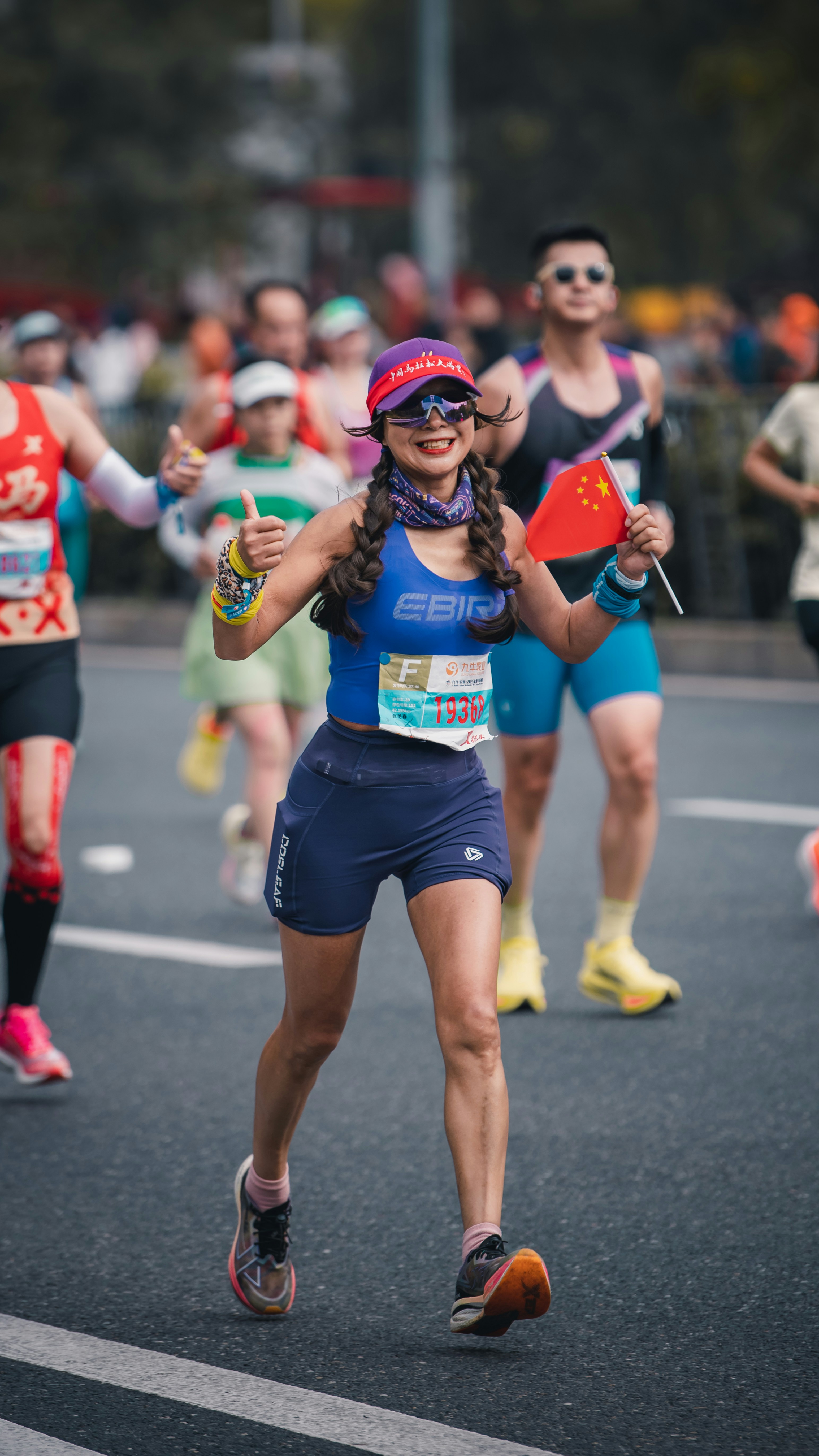 Woman runs marathon holding chinese flag and giving thumbs up