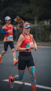 Woman running a marathon with colorful visor and taped legs