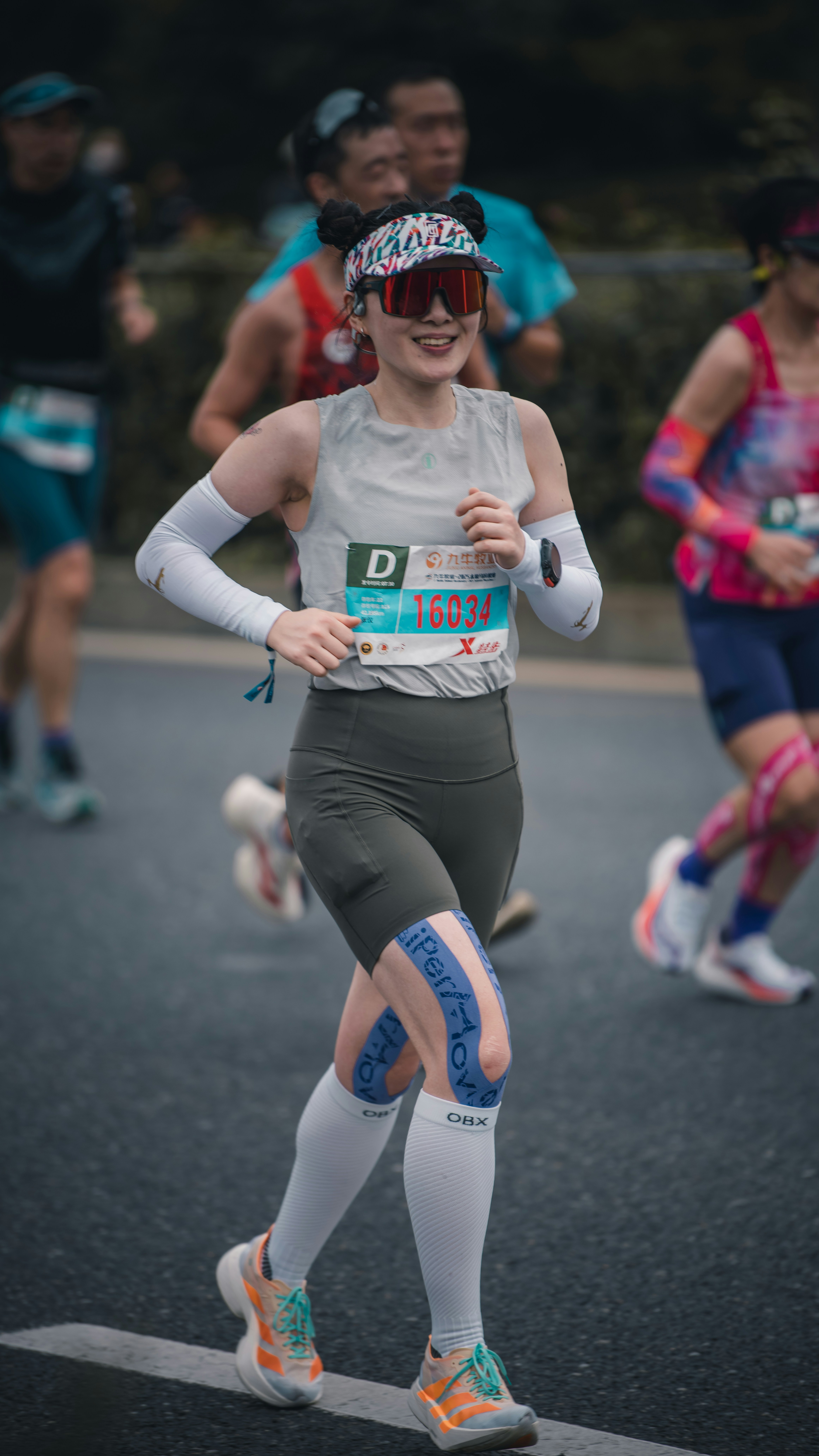 Woman running a marathon with other racers behind her.