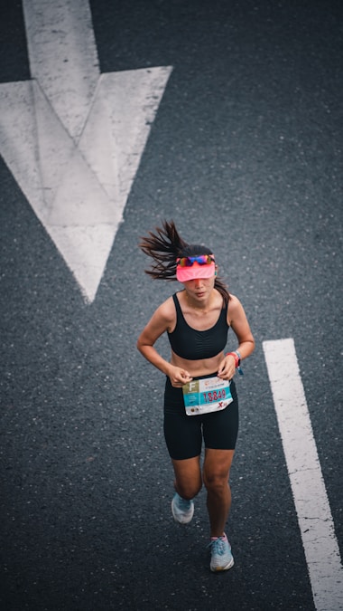 Woman running along a road course past a large directional arrow marker
