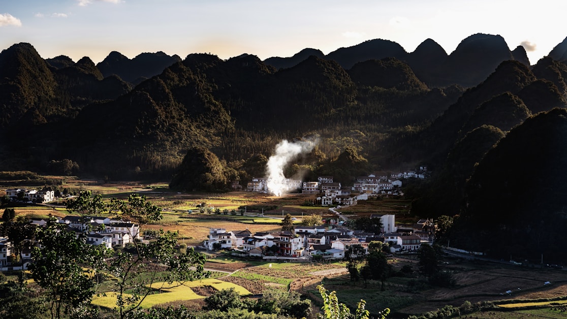 hidden villages china - small village among rolling green hills at sunset