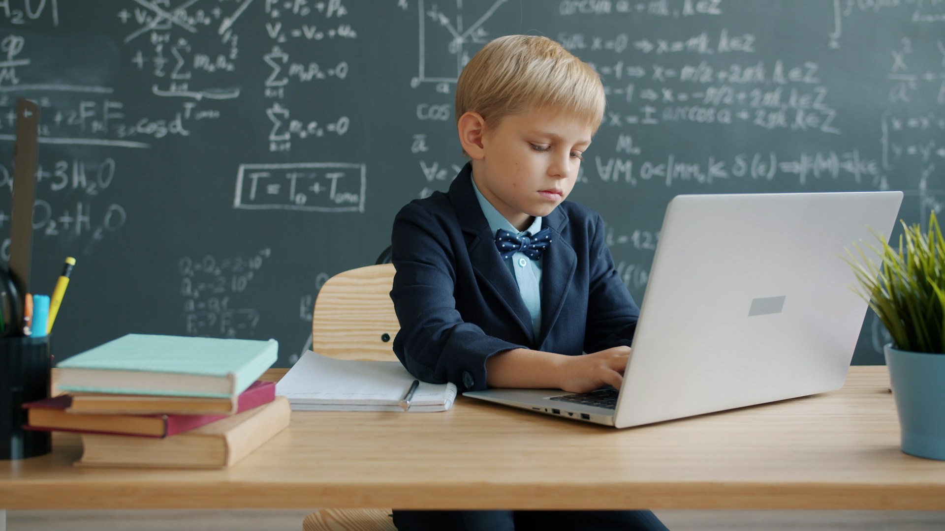 Boy in suit using laptop in classroom
