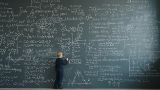 Young boy writing complex formulas on a chalkboard