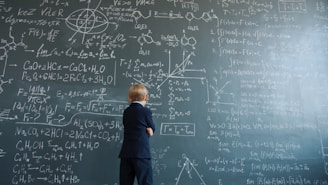 Young boy in suit studies complex math equations on blackboard