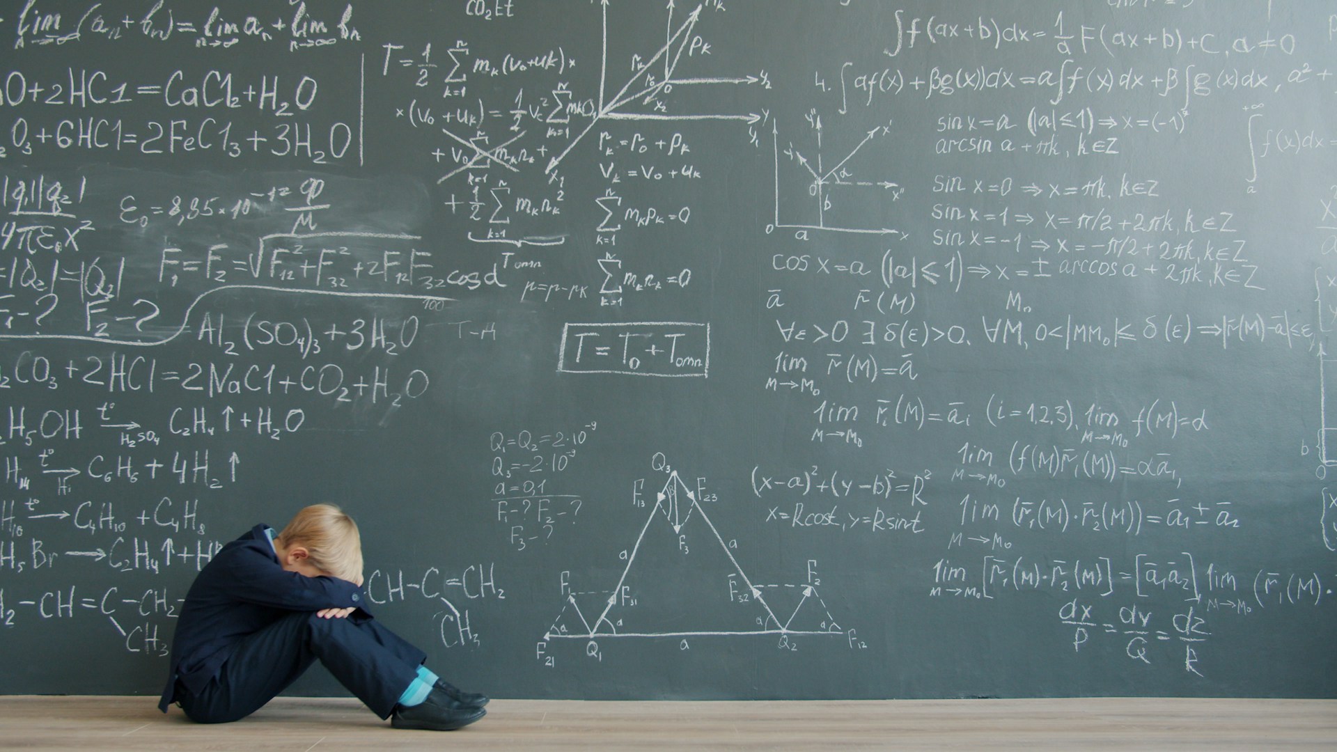 Student sits by blackboard covered in math equations