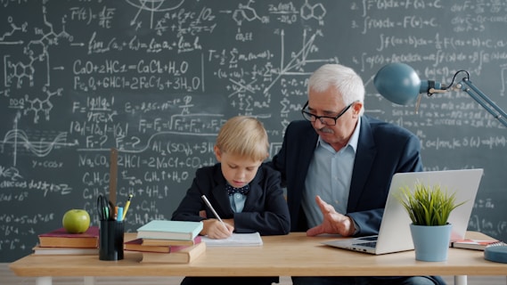 Elderly man teaching young boy math at desk.