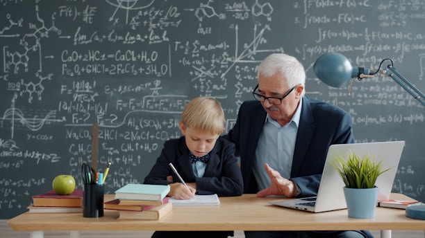 Elderly man teaching young boy math at desk.