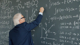 Professor writing mathematical formulas on a chalkboard.