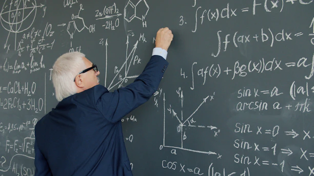 Professor writing mathematical formulas on a chalkboard.