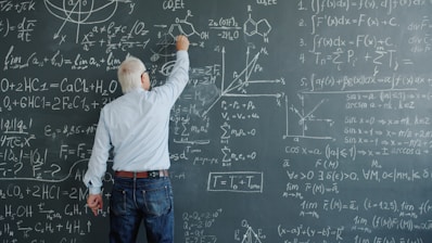 A professor writing complex formulas on a blackboard.